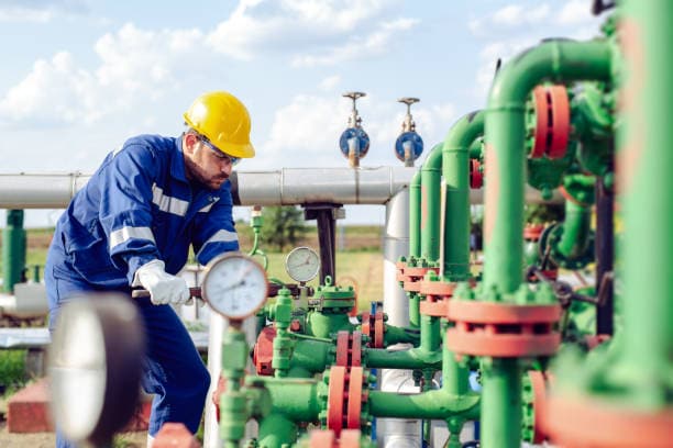 worker adjusting gauge at oil refinery